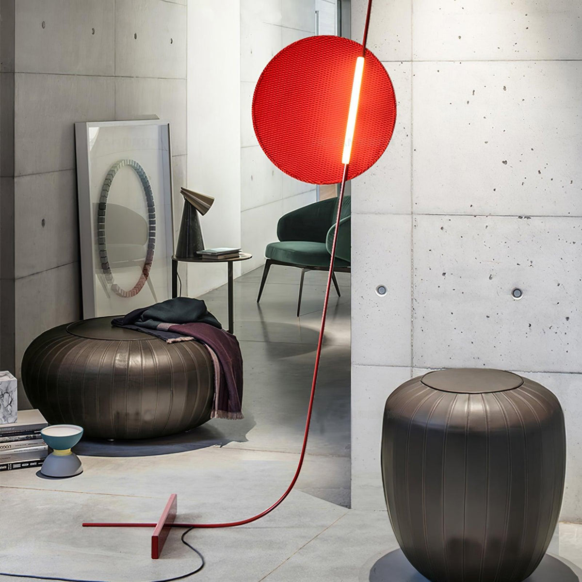 Lámpara de pie LED roja con disco de luz y varilla curva Oriola – junto a un puf metálico y un espejo