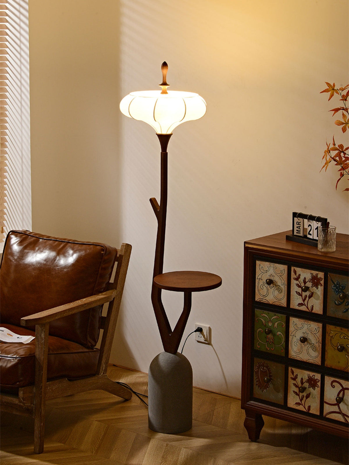 Lámpara de pie de madera con bandeja Ulmea – junto a una butaca de cuero y un mueble pintado