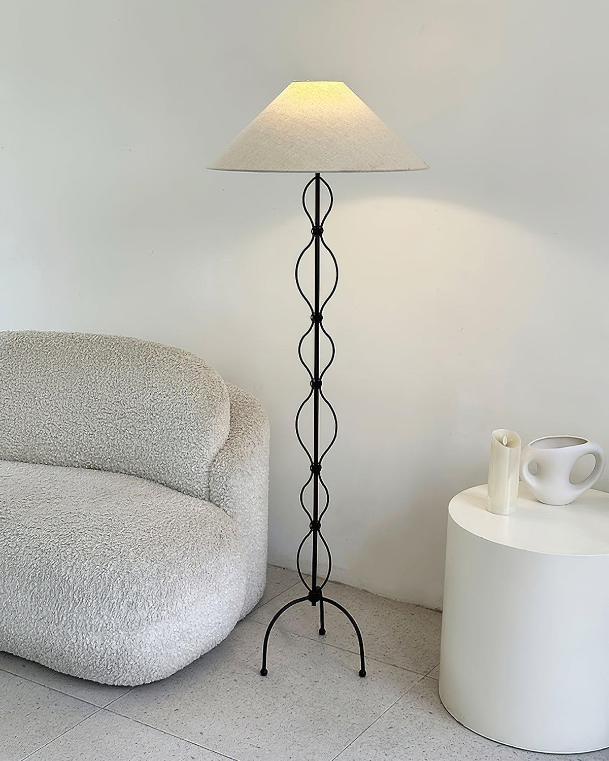 Lámpara de pie de hierro forjado Rizalia – junto a un sillón bouclé