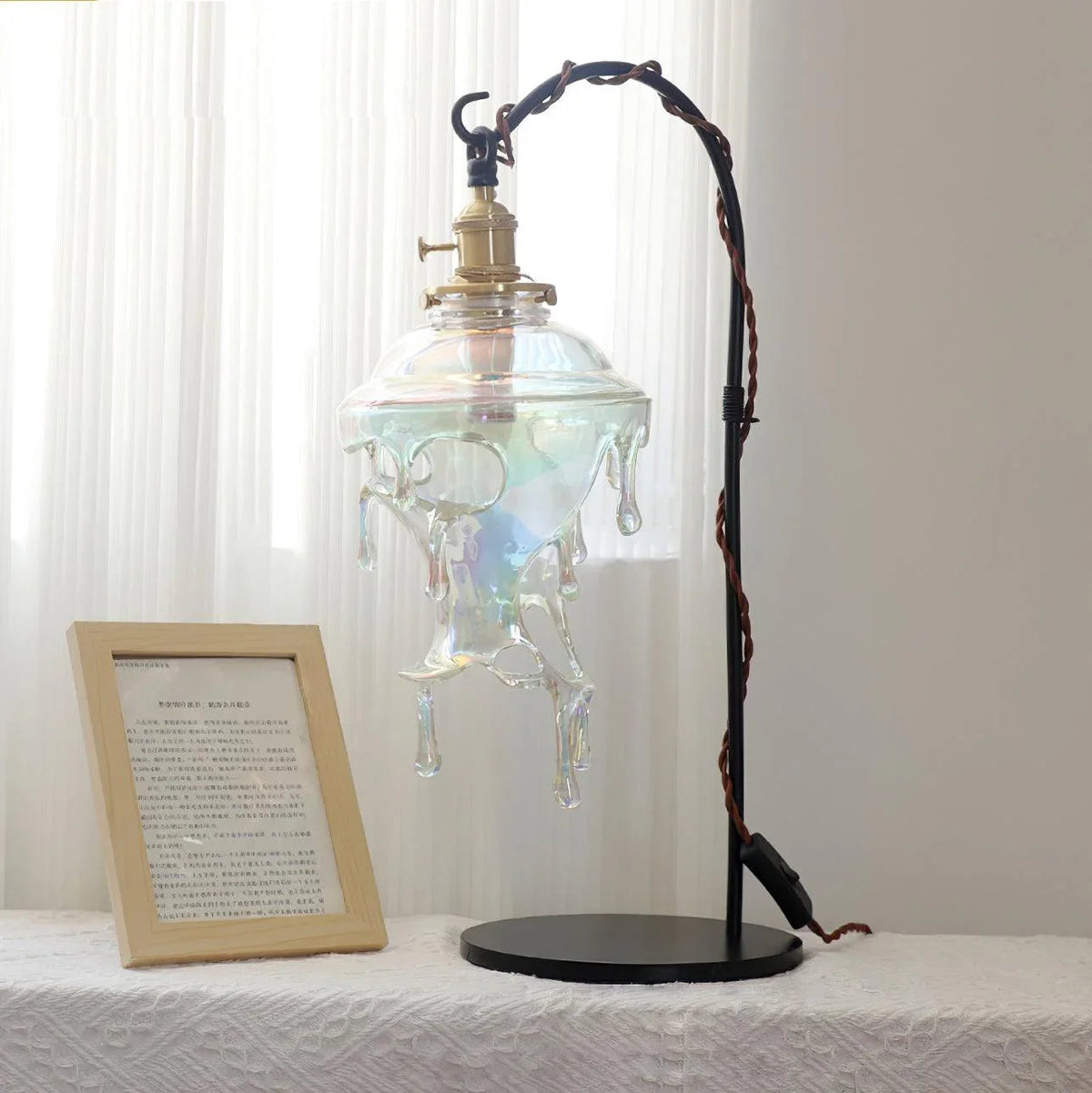 Lámpara de mesa de cristal Rociela – con cristal transparente sobre una mesa blanca