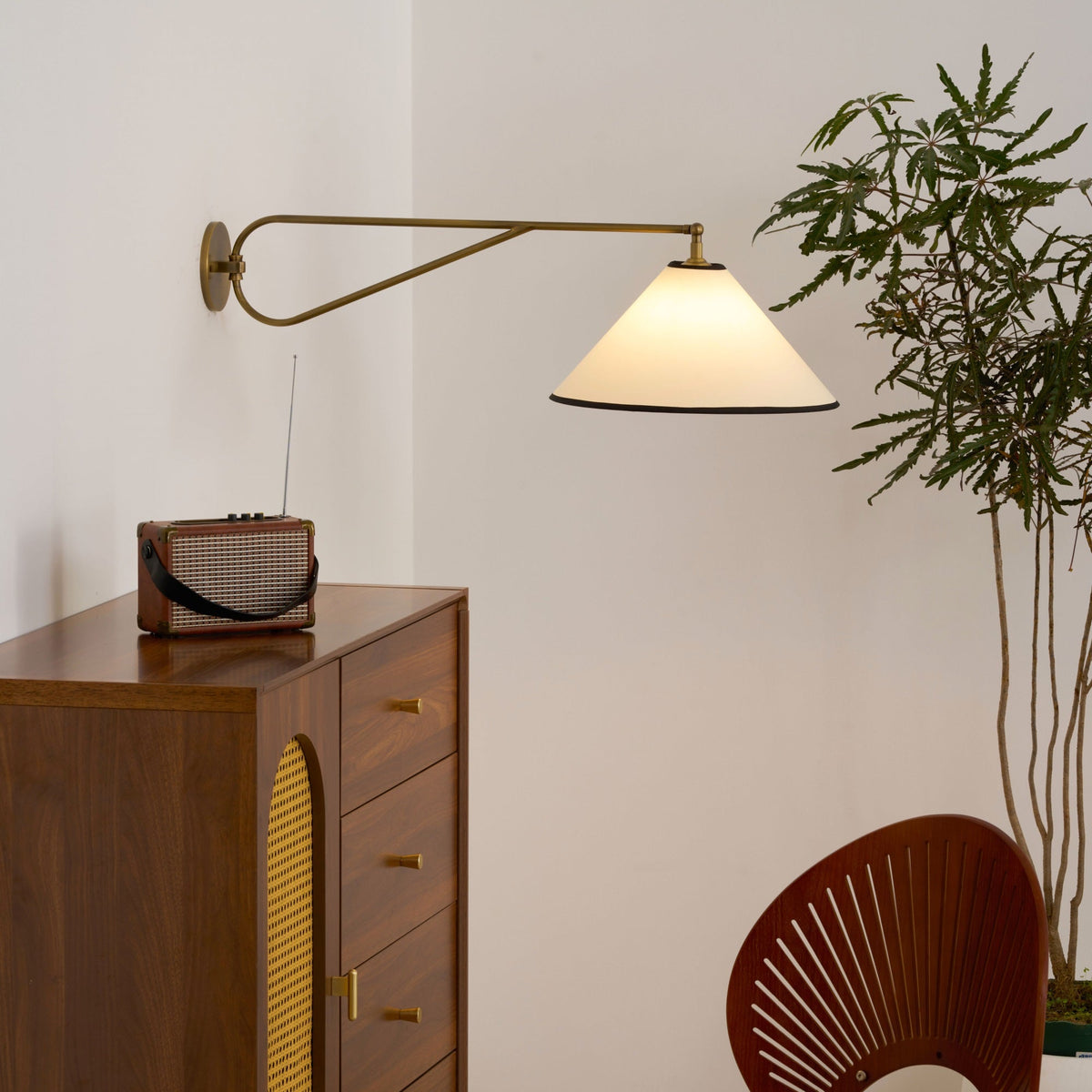 Aplique de pared con brazo giratorio Jalvira – junto a una cómoda de madera