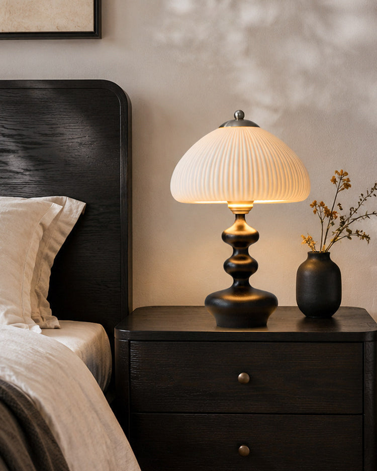 Lámpara de mesa de madera torneada Ruecola – en negro en una mesilla de noche