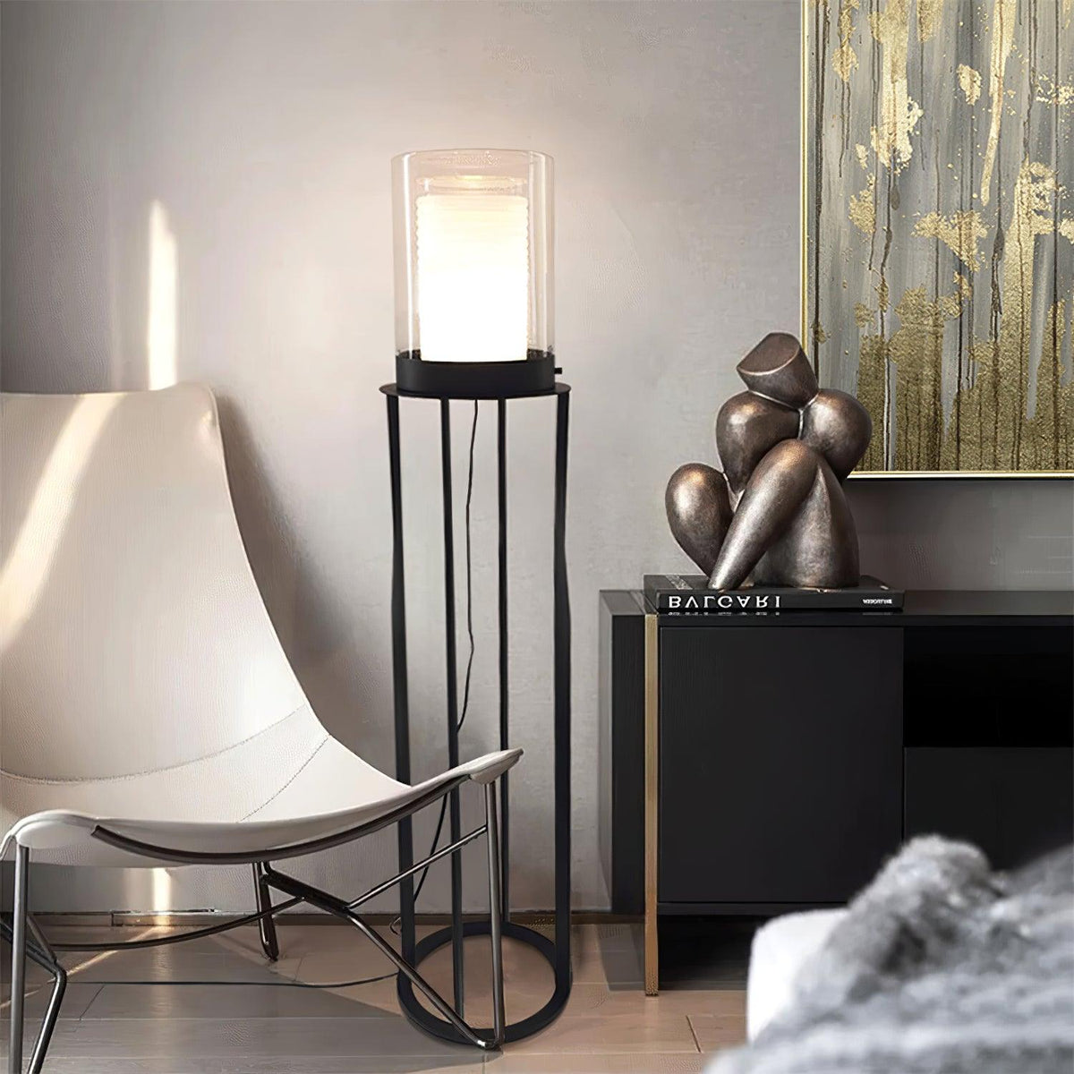 Lámpara de pie LED de doble cilindro de vidrio y estructura negra Navira – junto a un sillón blanco y una escultura