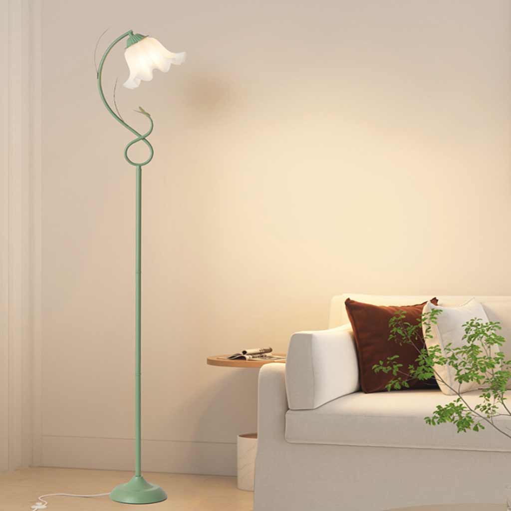 Lámpara de pie flor Zarcilla – verde encendida junto a un sofá blanco