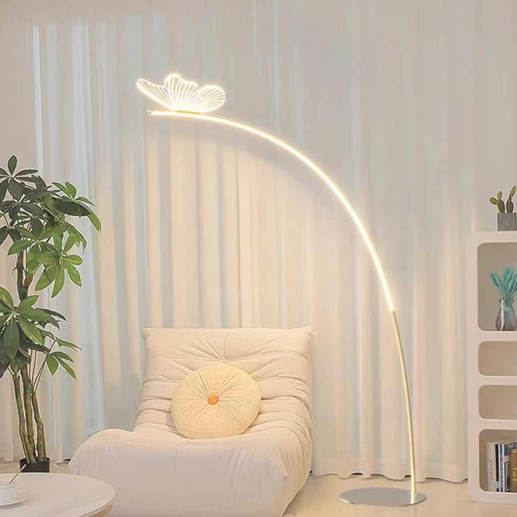 Lámpara de pie de arco con mariposa Sualeta – junto a un sillón bajo