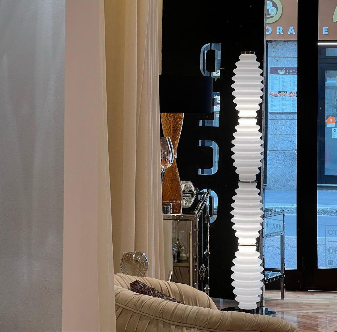Lámpara de pie de cristal Tulara – en un salón con cortinas