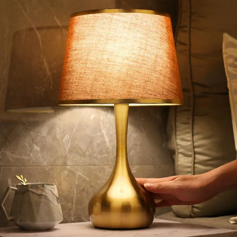 Lámpara de mesa con base dorada Orvala – pantalla marrón encendida