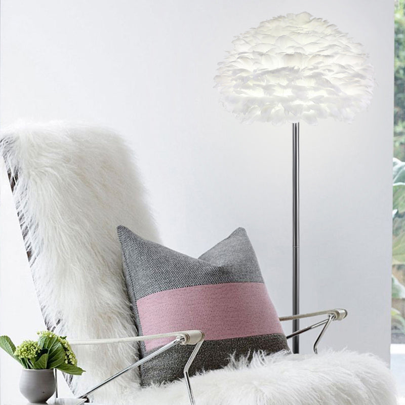 Lámpara de pie con pantalla de plumas blancas Sedara – pie único cromado junto a un sillón