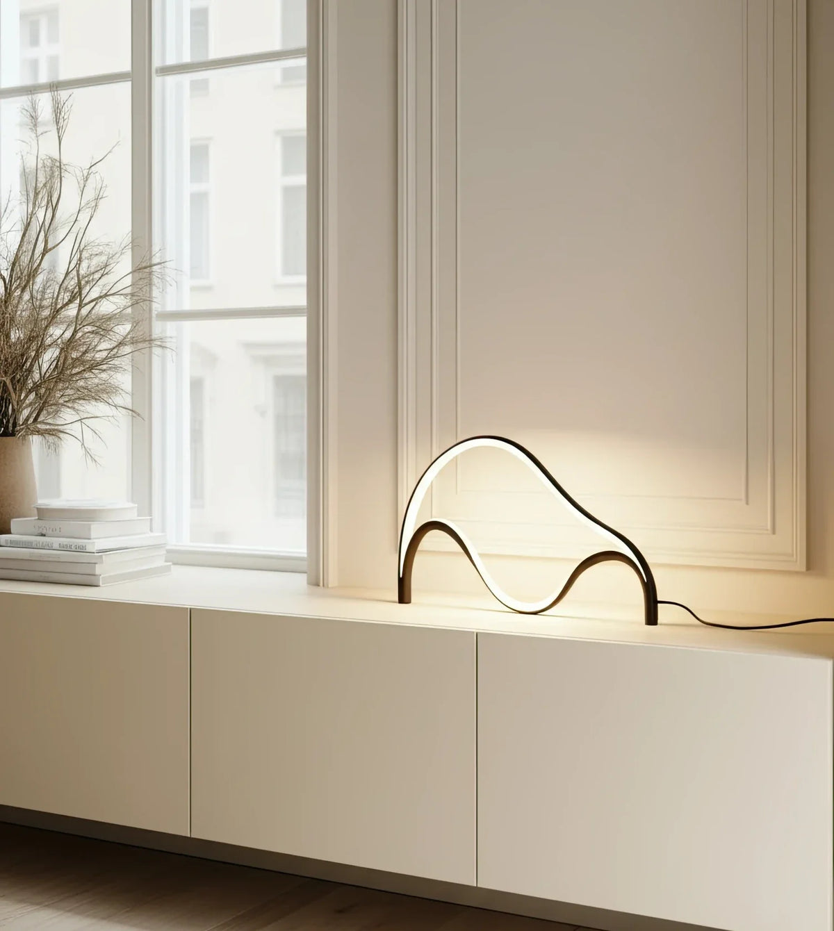 Lámpara de mesa LED escultural Mondea sobre un aparador blanco – imagen 2