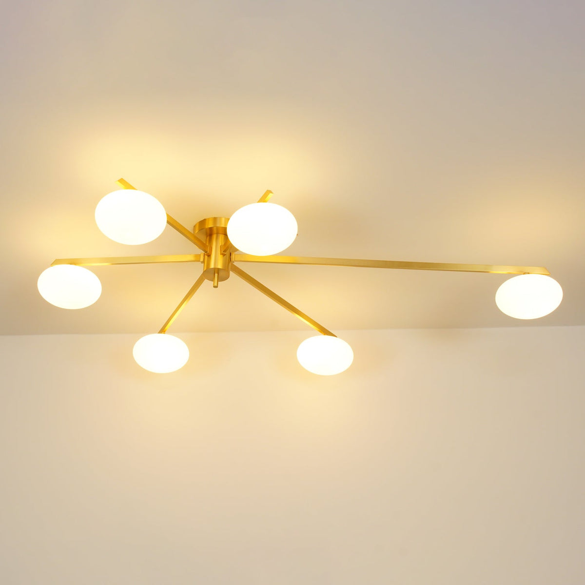 Lámpara de techo de brazos Estrela – dorada encendida con luz cálida