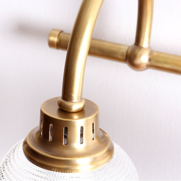 Aplique de pared Yarela con cristal estriado y latón – detalle del brazo curvo