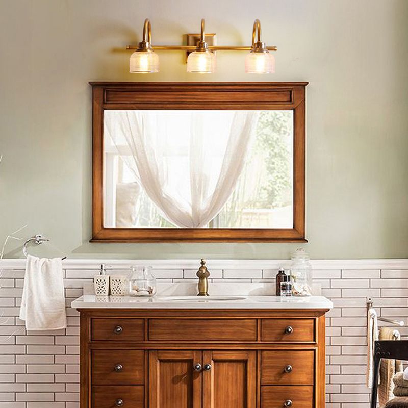 Aplique de pared Yarela con cristal estriado y latón – versión de 3 luces sobre un mueble de lavabo