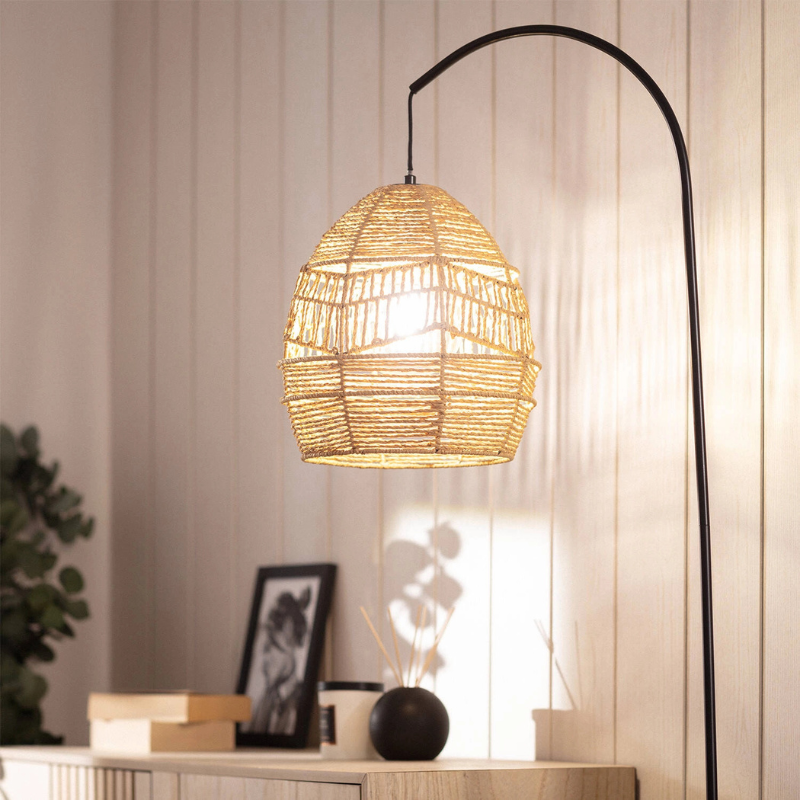 Lámpara de pie arco Tenara con pantalla de fibra natural – encendida junto a un aparador