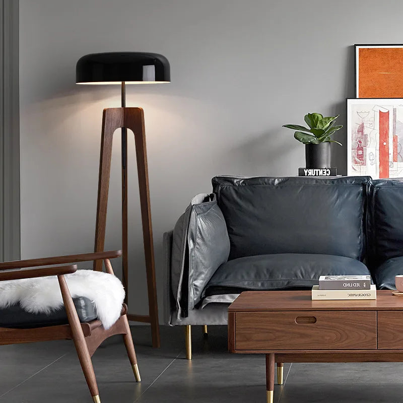 Lámpara de pie trípode Usiba de madera y negro – en un salón con sofá de piel