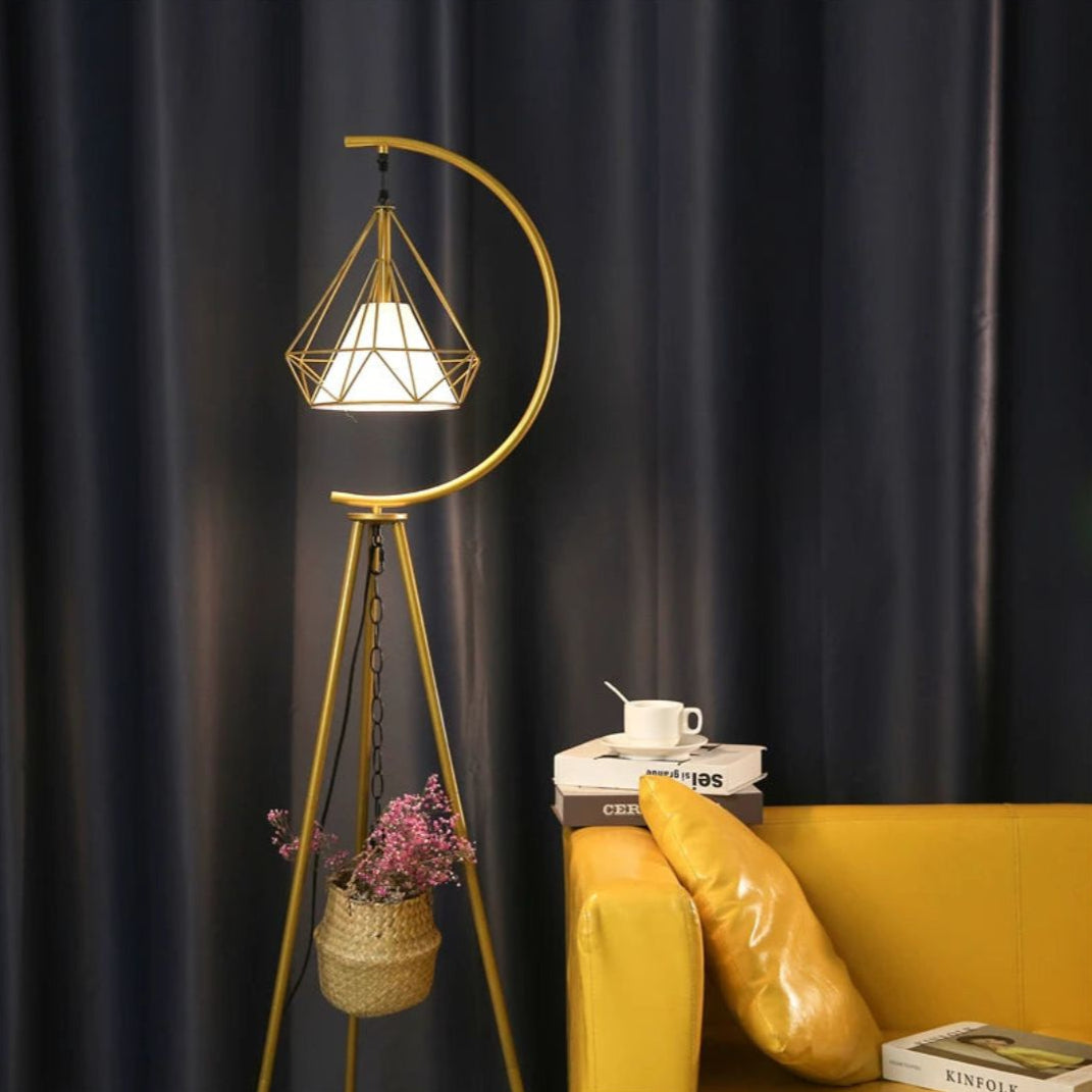 Lámpara de pie trípode con jaula de diamante Sidiana – en dorado junto a un sillón