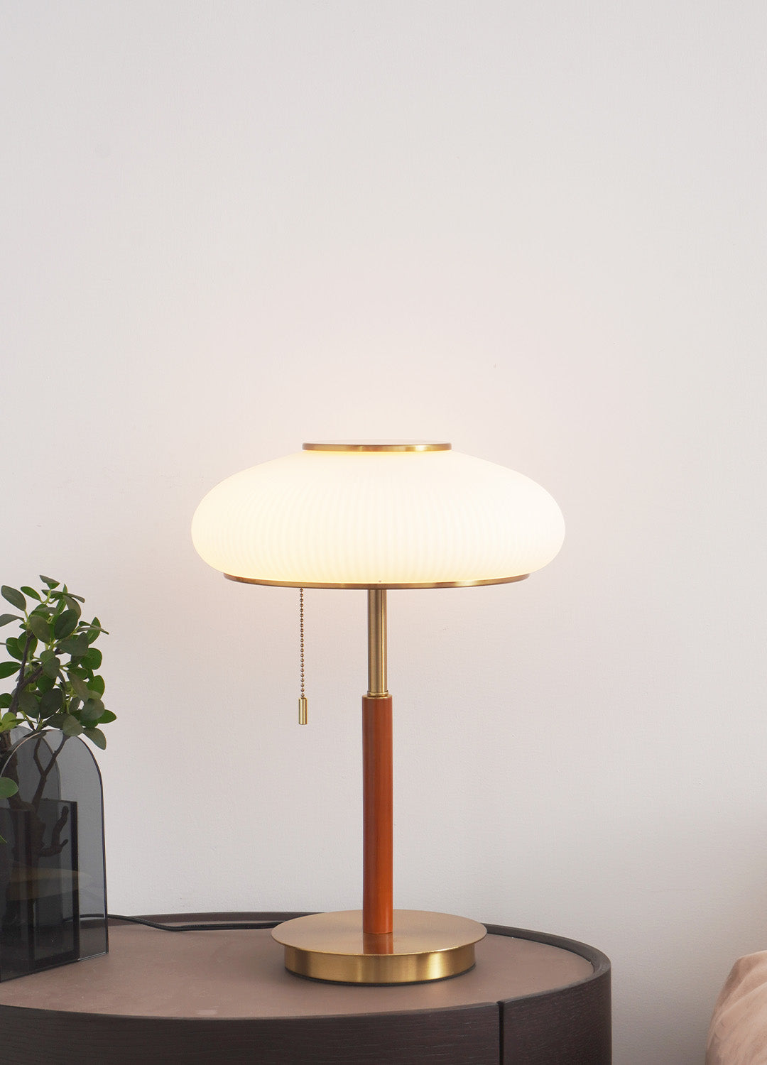 Lámpara de mesa vintage Rizala – encendida junto a una planta