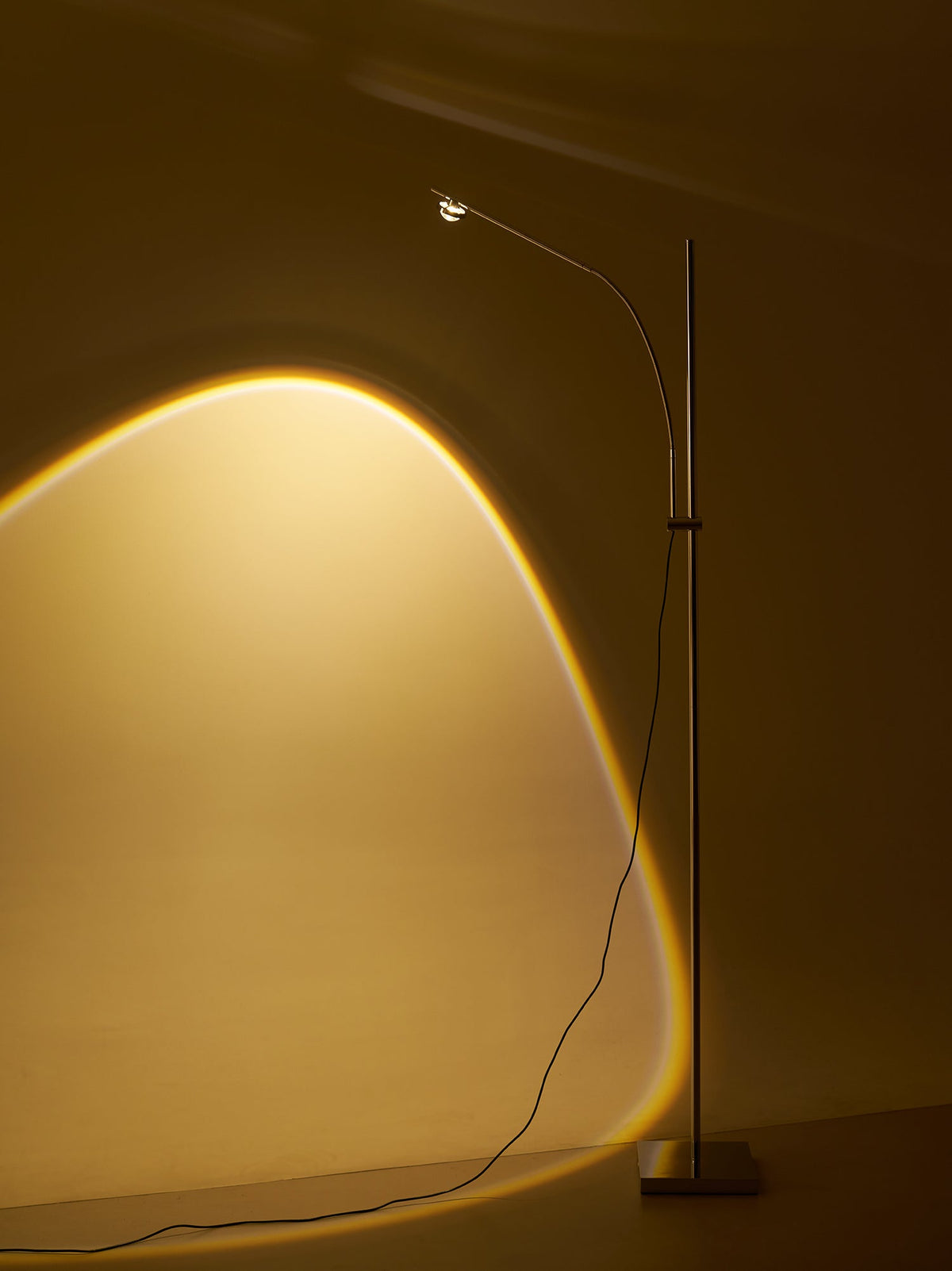 Lámpara de pie LED arqueada Vareta – vista completa junto a un sofá