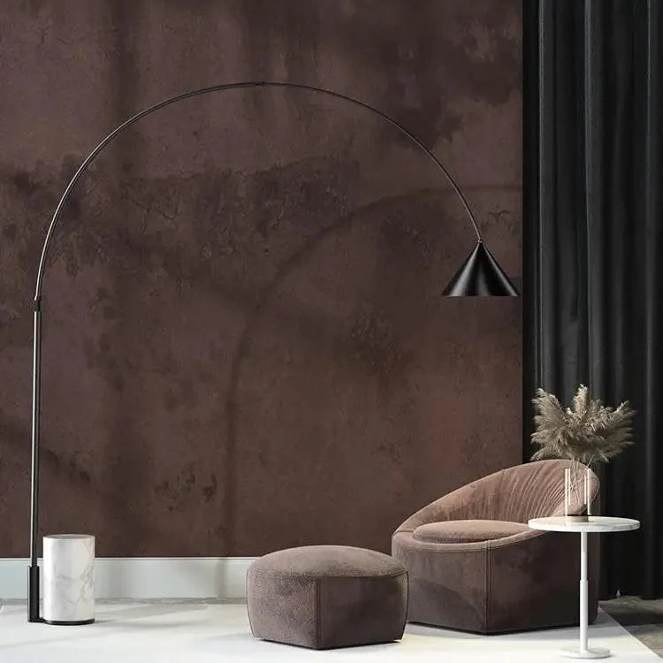 Lámpara de pie de arco Sauceda – junto a un sillón y una mesa auxiliar