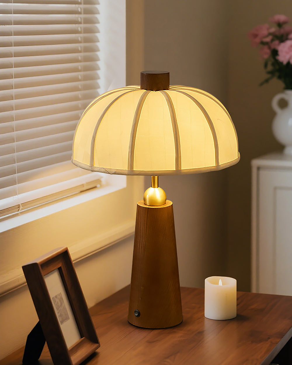 Lámpara de mesa de madera Toldina – encendida junto a una ventana con flores