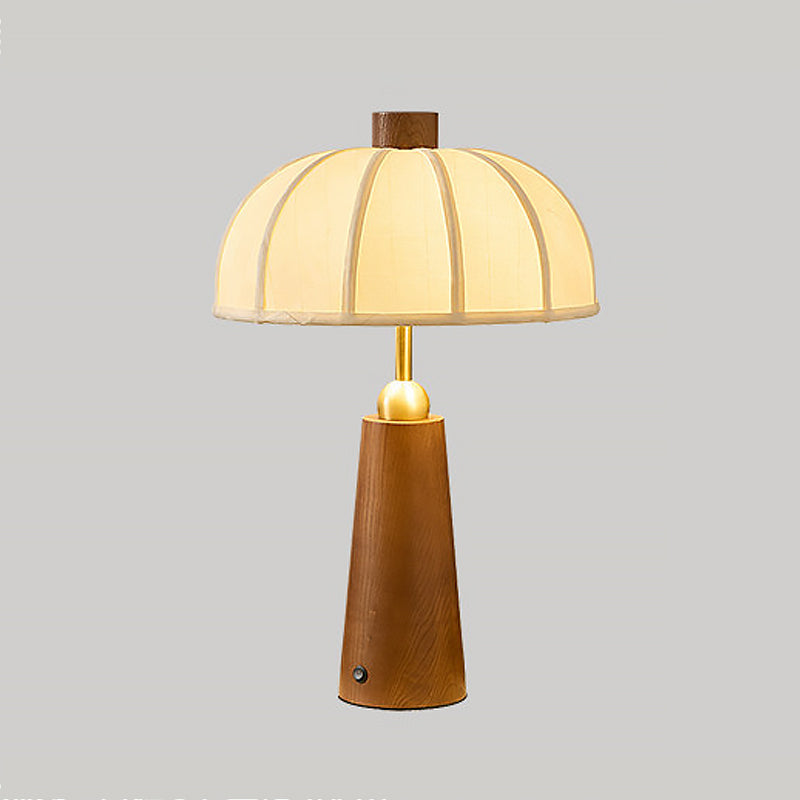 Lámpara de mesa de madera Toldina – nogal y dorado encendida sobre fondo gris