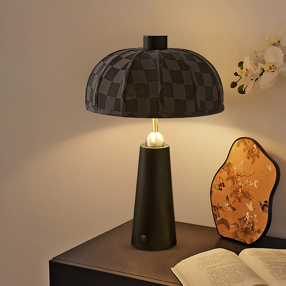 Lámpara de mesa de madera Toldina – negra encendida sobre una mesilla