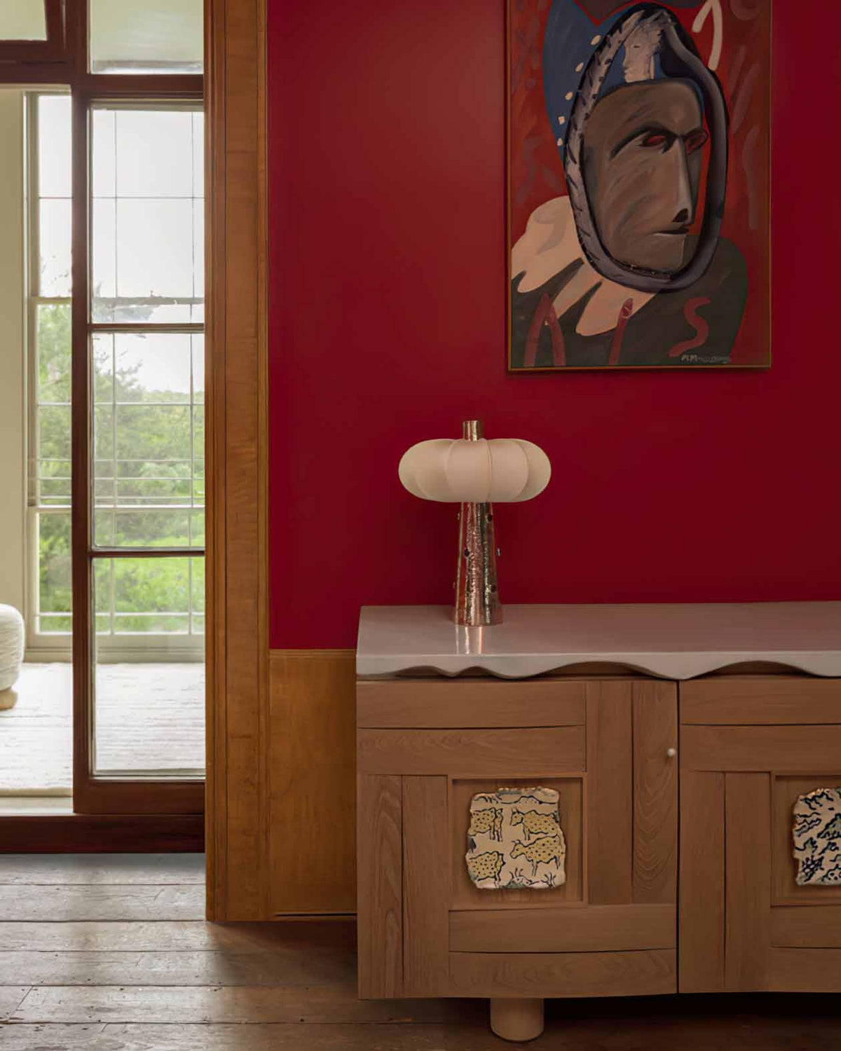 Lámpara de mesa plateada Rubela – sobre un aparador frente a una pared roja