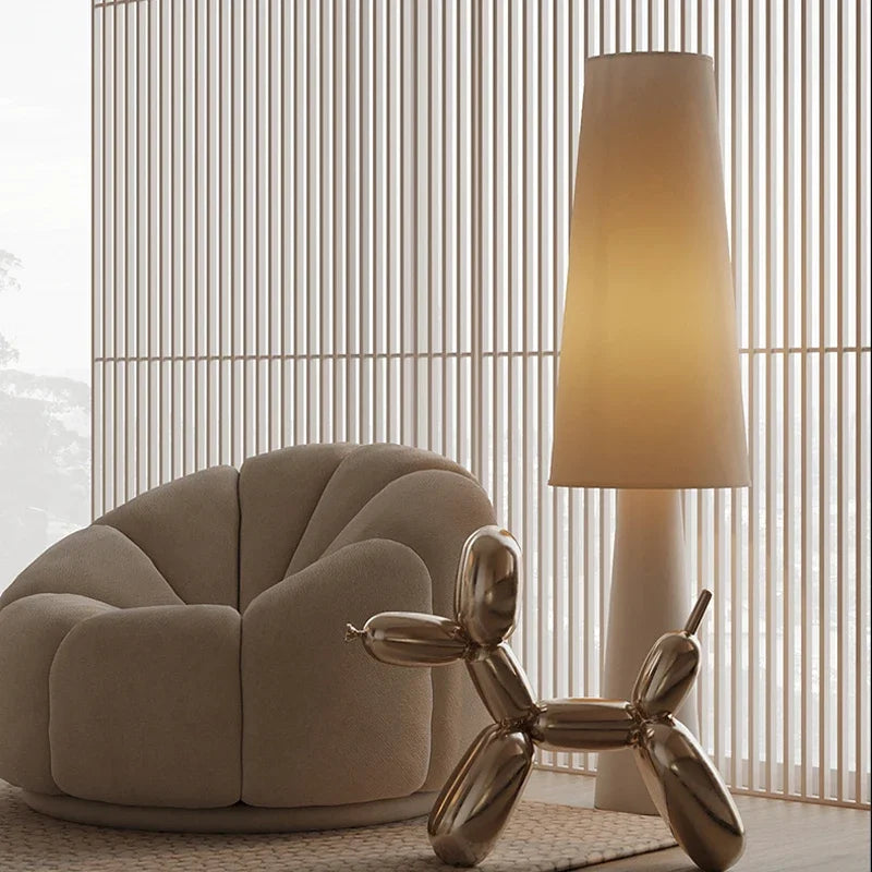 Lámpara de pie wabi sabi Ustela con pantalla de tela – junto a un sillón redondeado
