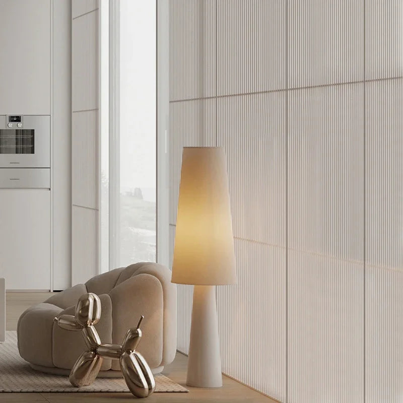 Lámpara de pie wabi sabi Ustela con pantalla de tela – junto a un sillón en un salón claro