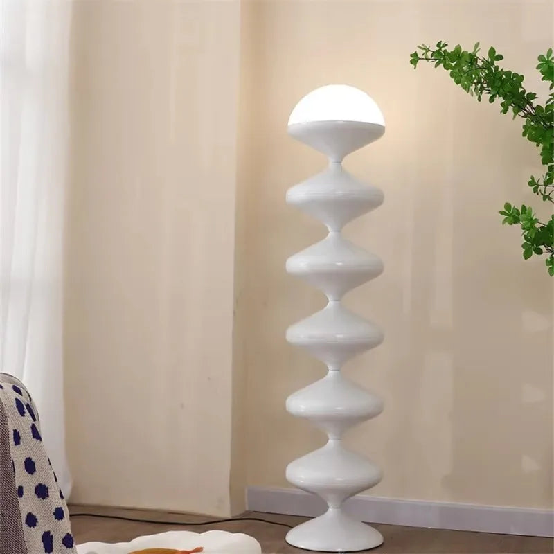 Lámpara de pie escultórica Yoyela – en blanco lechoso junto a una ventana