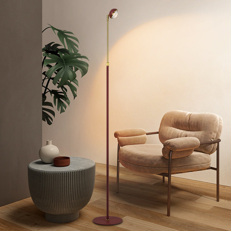Lámpara de pie minimalista Solvira – rojo burdeos junto a un sillón
