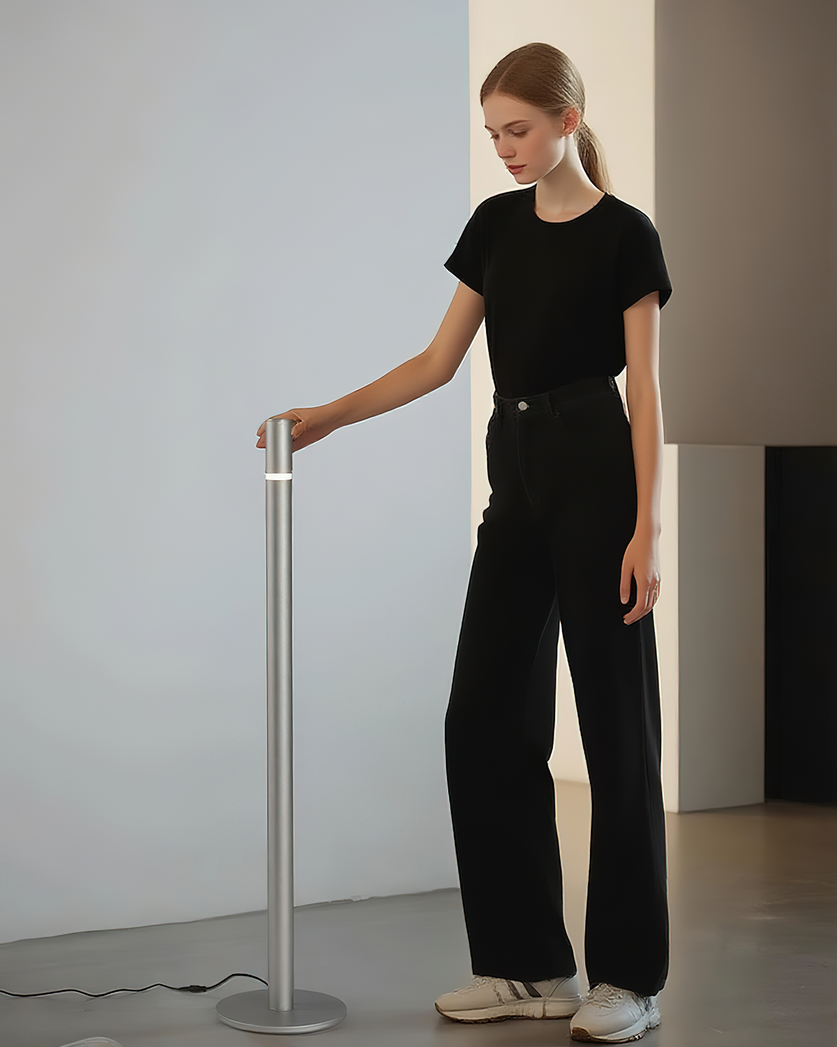 Lámpara de pie LED columna Tizona – plateada junto a una persona