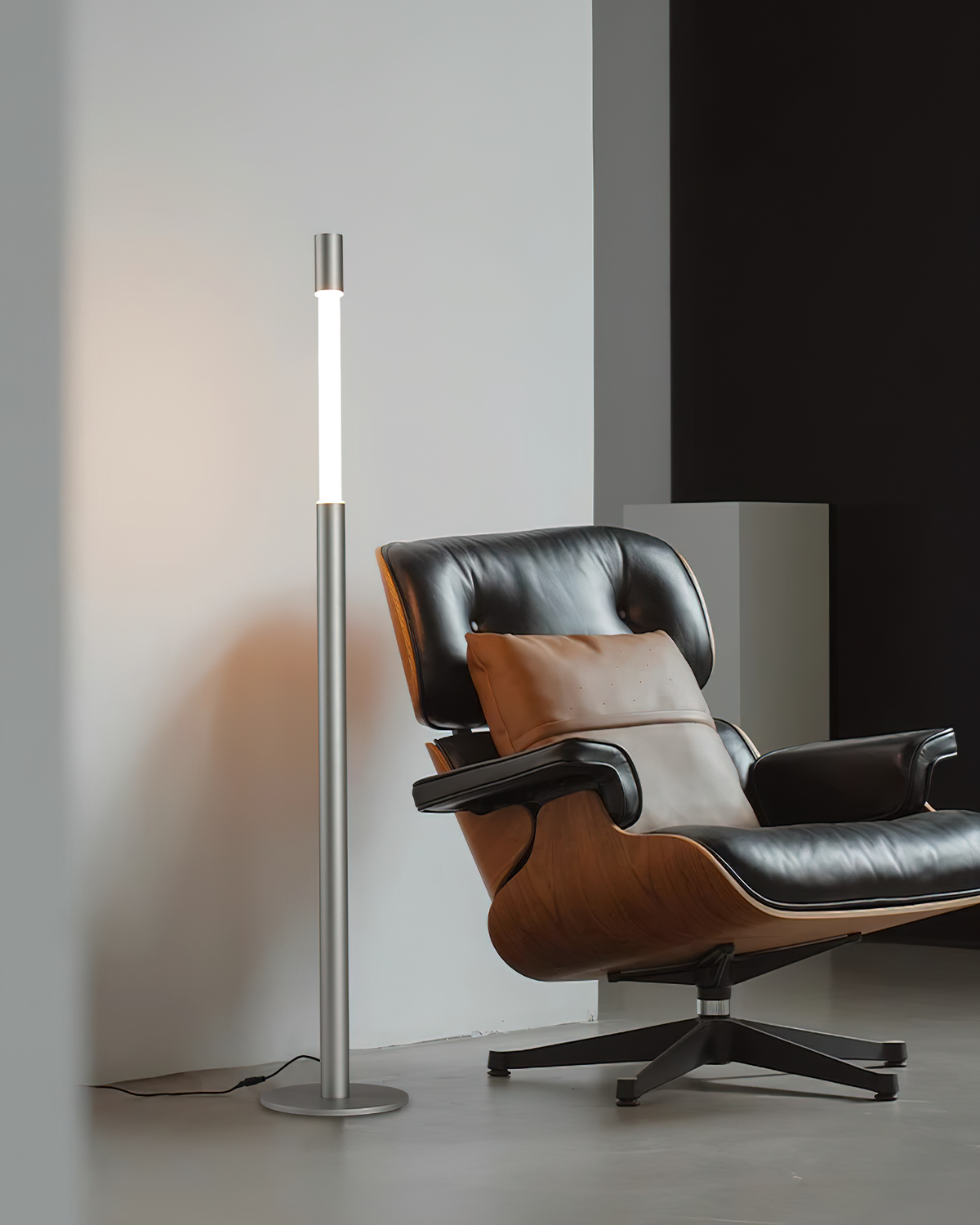 Lámpara de pie LED columna Tizona – plateada junto a un sillón de piel