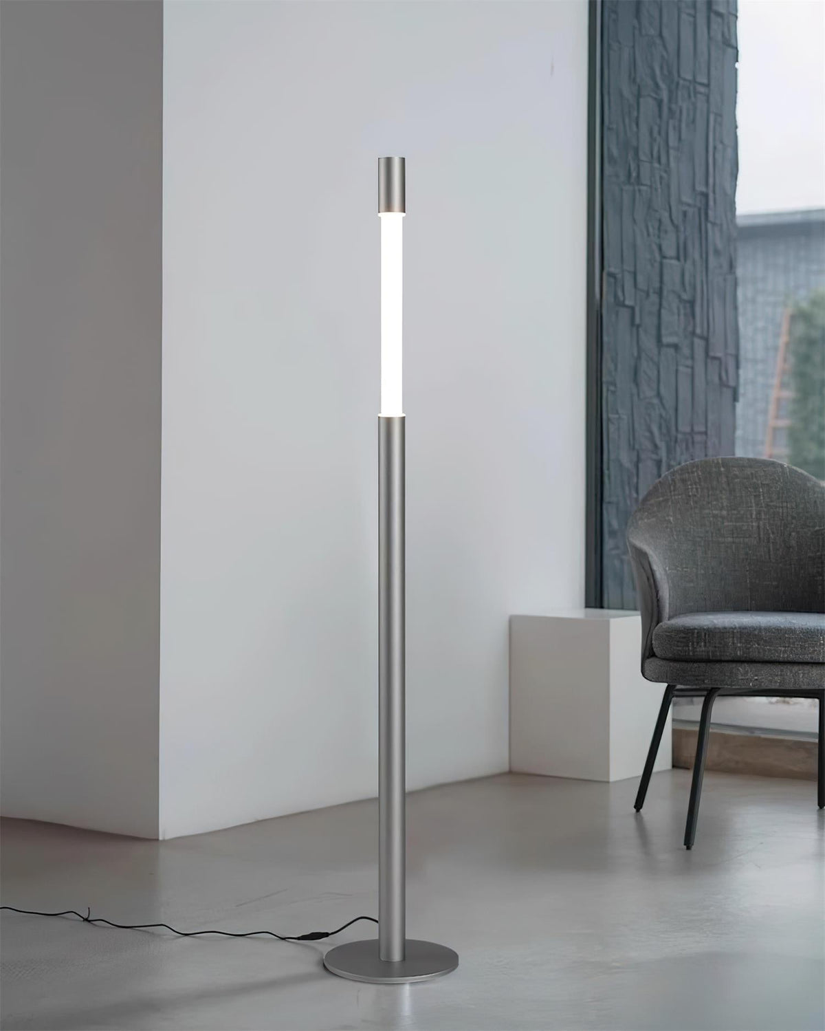 Lámpara de pie LED columna Tizona – plateada junto a una butaca