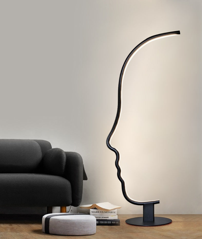 Lámpara de pie LED con silueta de rostro Quiara – junto a un sofá gris