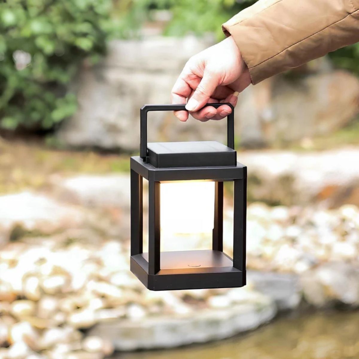 Farol solar LED portátil Jolena – llevado de la mano por su asa