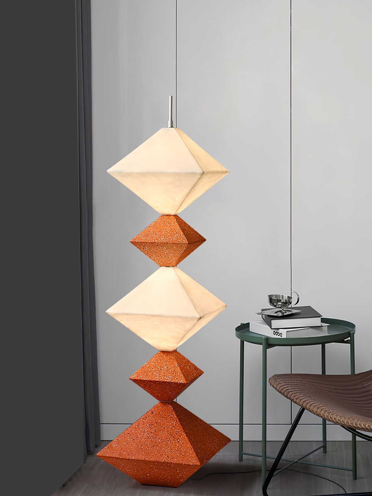 Lámpara de pie LED con rombos apilados Peluma – en naranja y blanco junto a una mesa auxiliar