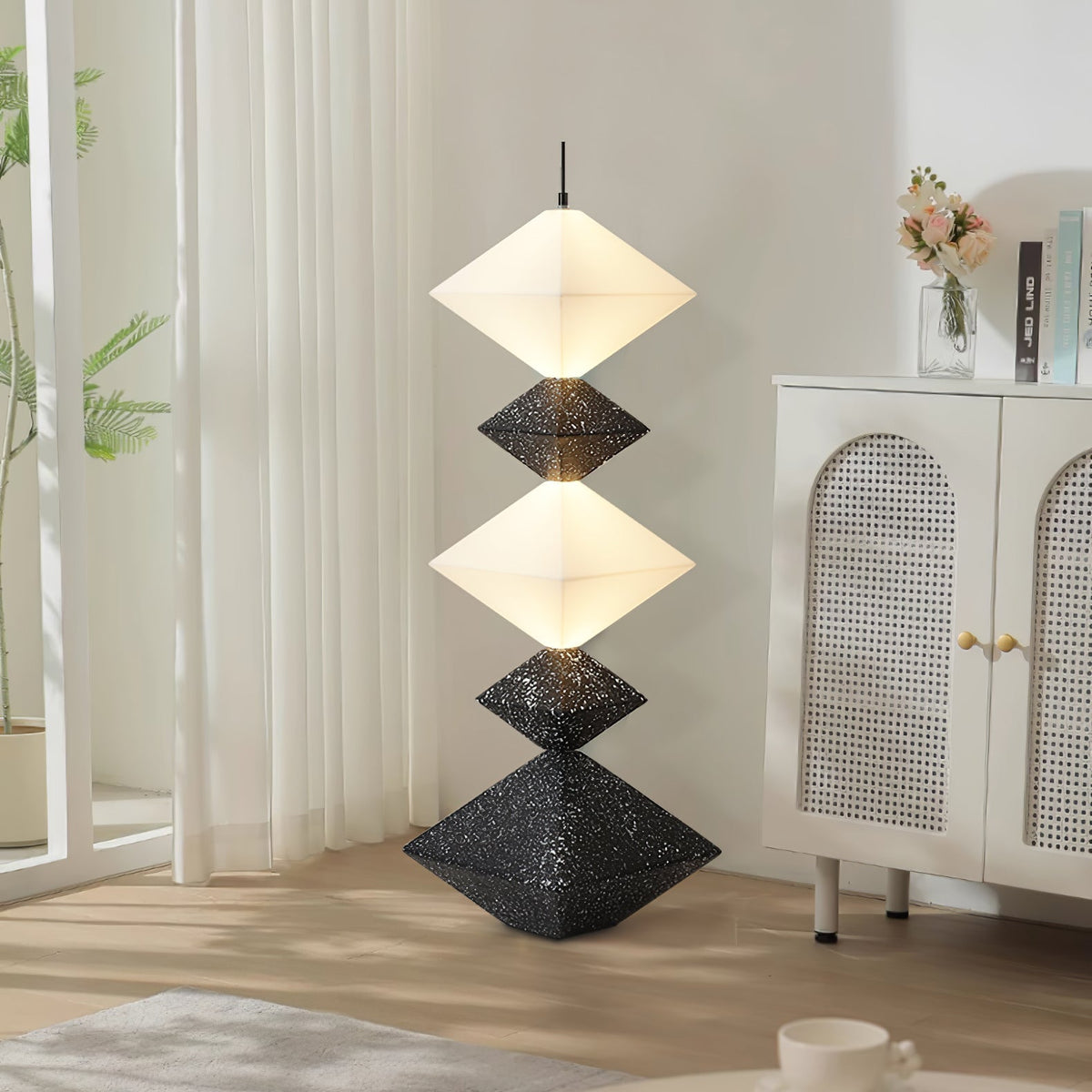 Lámpara de pie LED con rombos apilados Peluma – en negro y blanco junto a un aparador