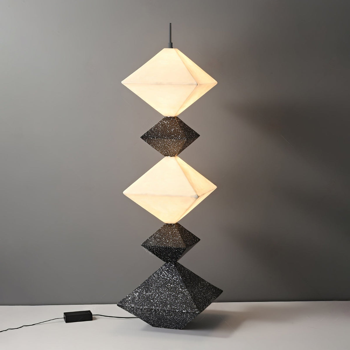 Lámpara de pie LED con rombos apilados Peluma – en negro y blanco sobre fondo gris