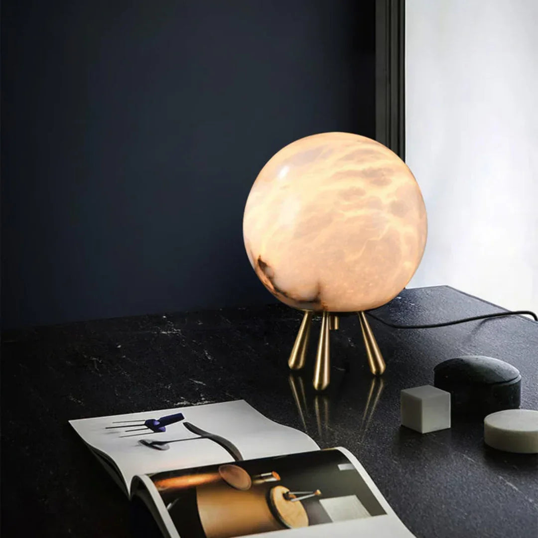 Lámpara de mesa de alabastro Selunia – junto a una revista sobre mesa negra