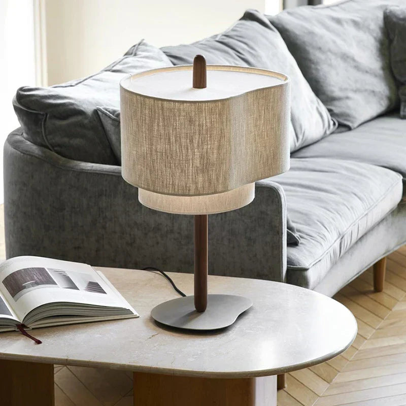 Lámpara de mesa wabi sabi Tapela – sobre una mesa de centro junto al sofá