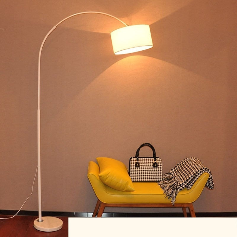 Lámpara de pie de arco Tendela – en blanco junto a un banco amarillo