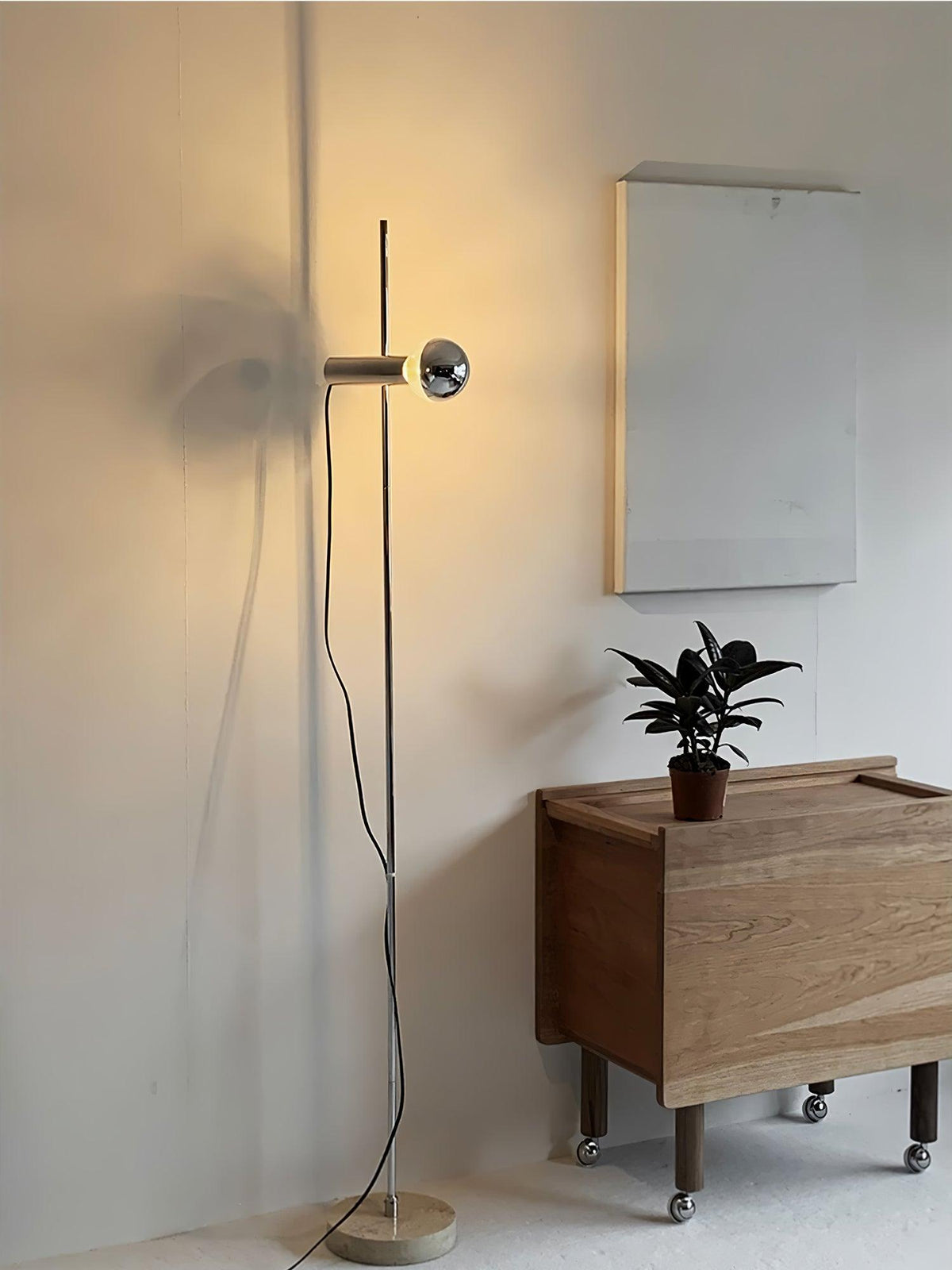 Lámpara de pie Tersia de acero y mármol beige – encendida junto a la pared