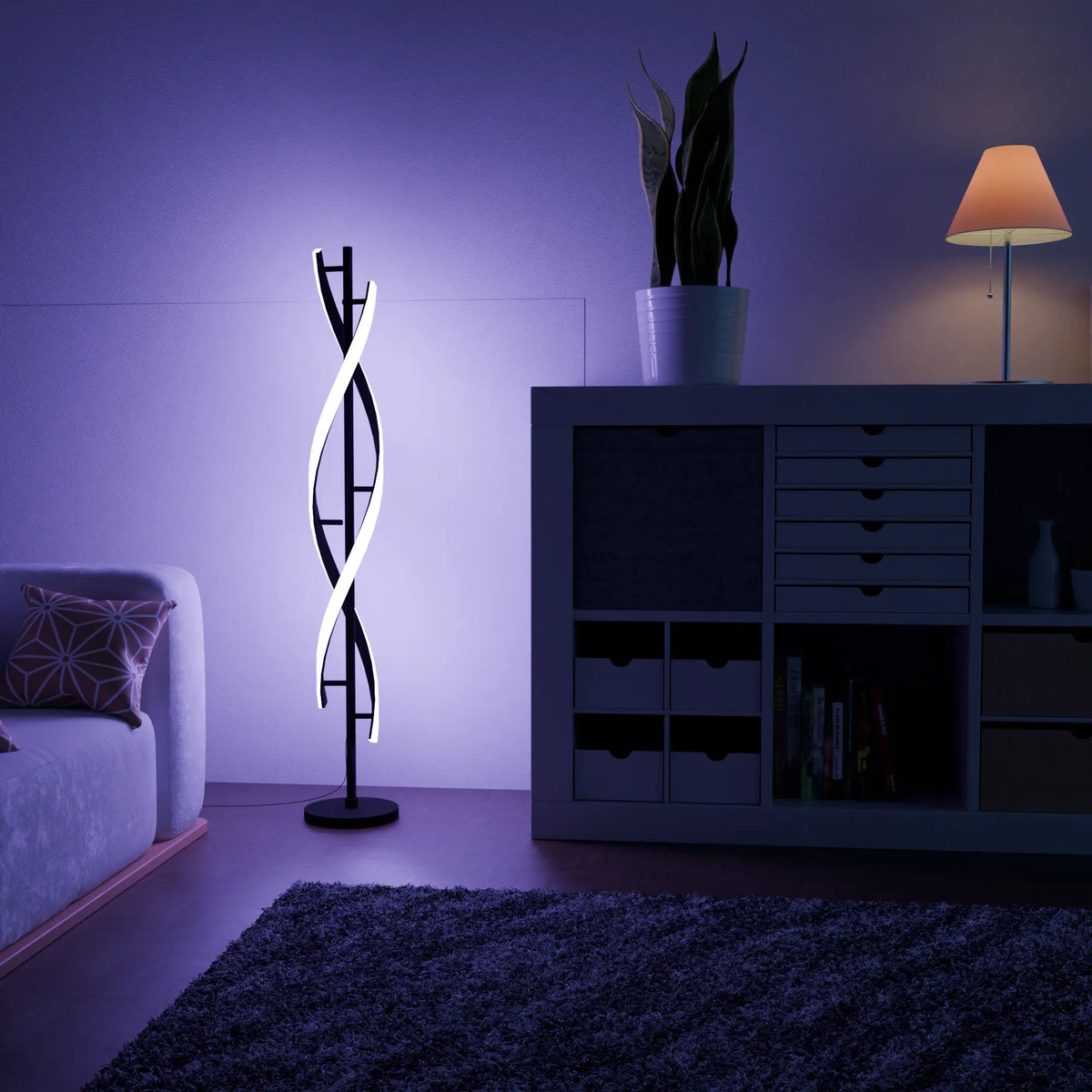Lámpara de pie LED en espiral Rizena – junto a una estantería con ambiente de color
