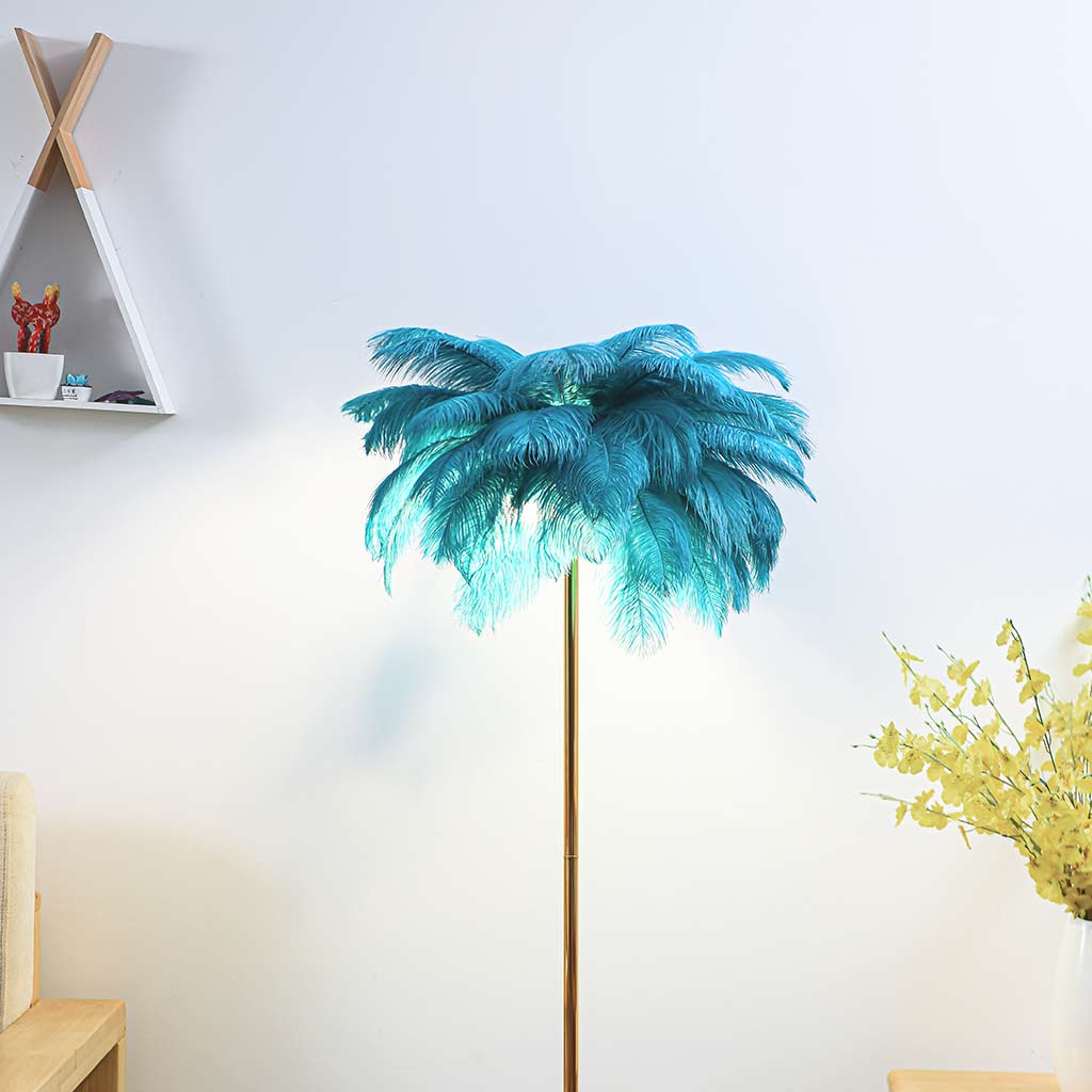 Lámpara de pie de plumas Truzela – verde azulado encendida junto a la pared