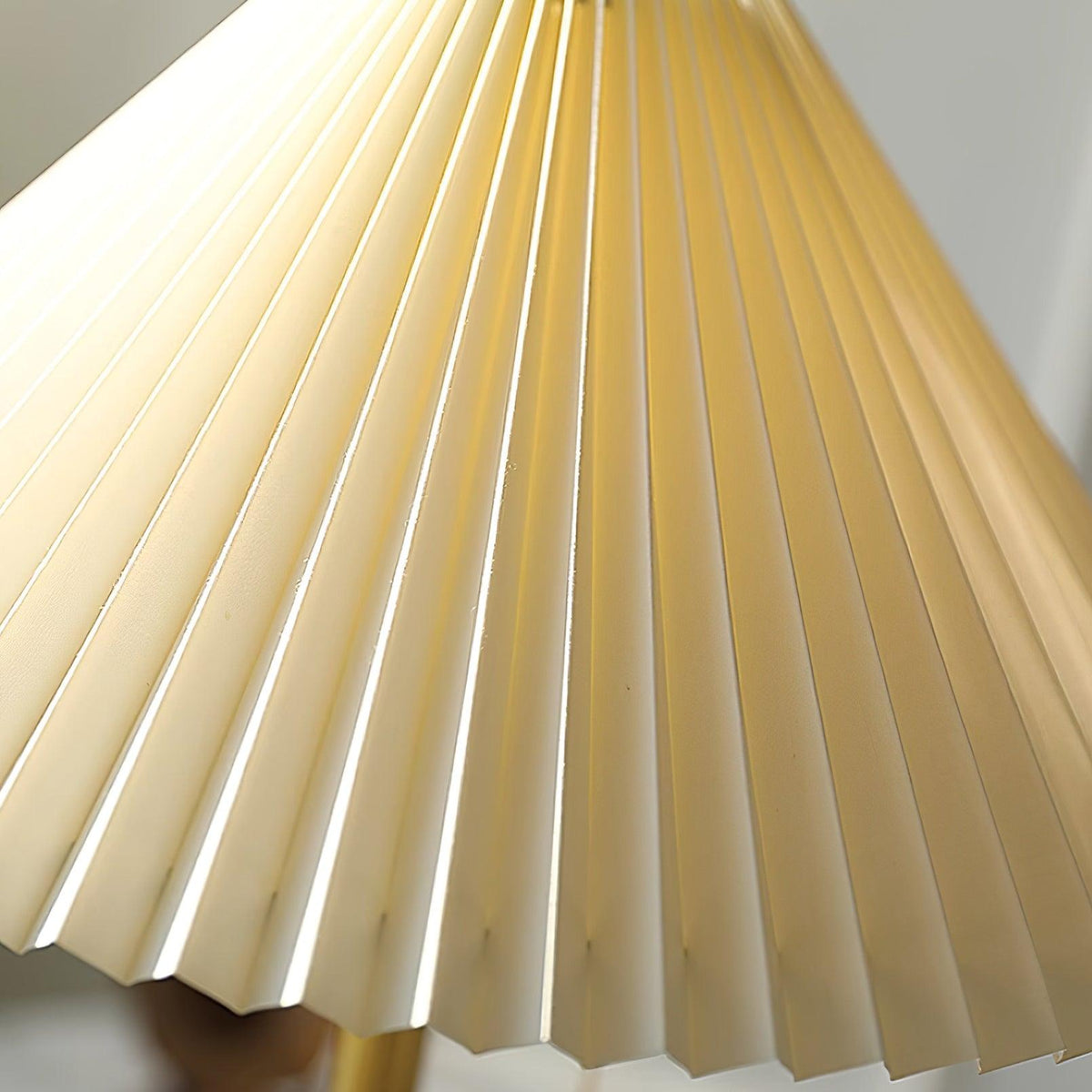 Lámpara de mesa plisada Ripela – sobre un mueble de madera