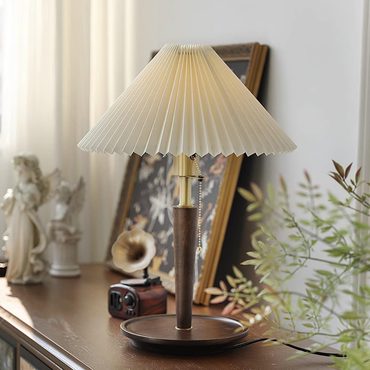 Lámpara de mesa plisada Ripela – en un rincón con plantas