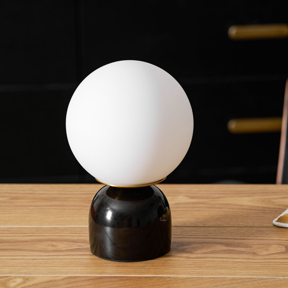 Lámpara de mesita Dunela con globo opal y base de mármol sobre una mesa de madera – imagen 22