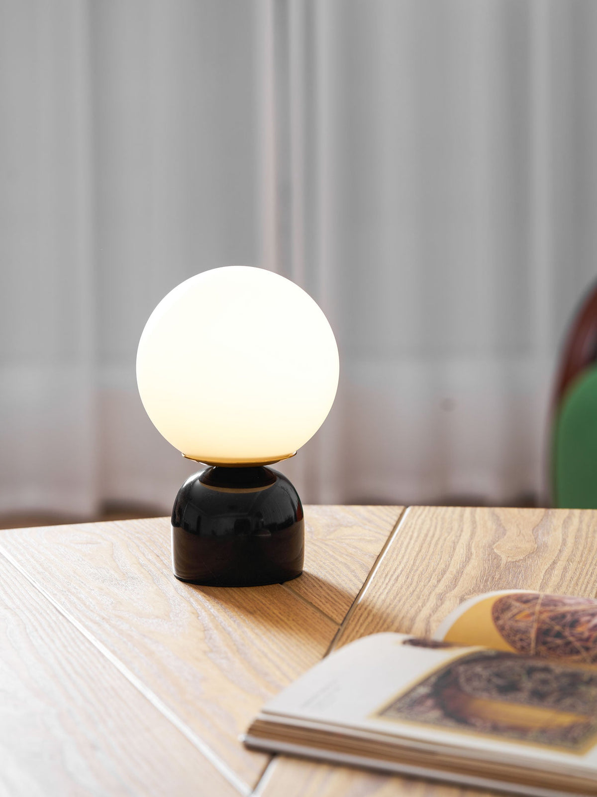 Lámpara de mesita Dunela con globo opal y base de mármol sobre una mesa de madera – imagen 23