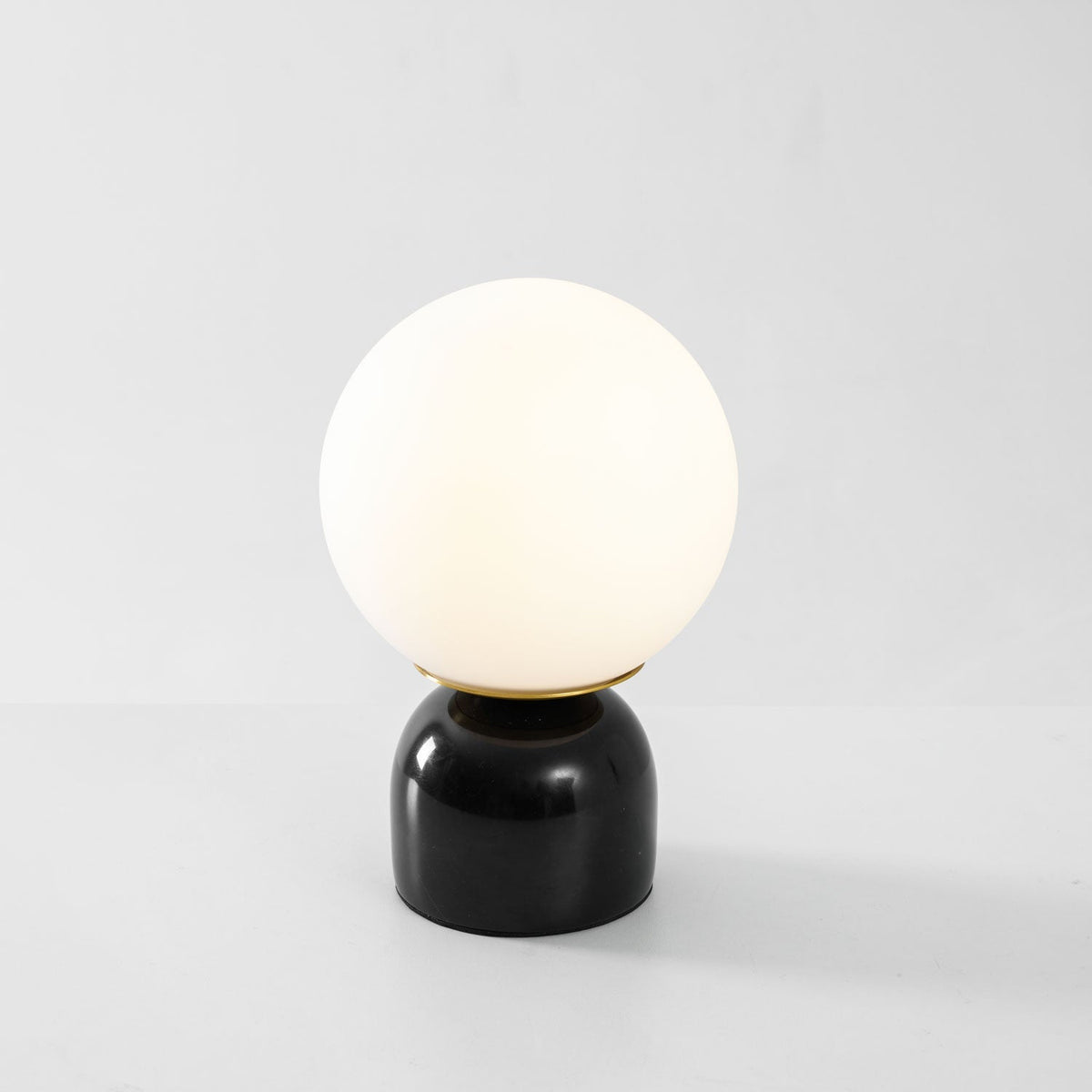 Lámpara de mesita Dunela con globo opal y base de mármol sobre una mesa de madera – imagen 24