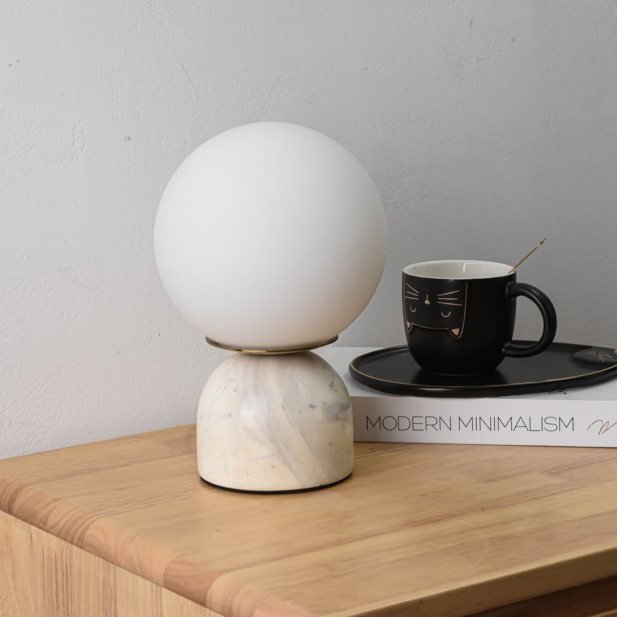Lámpara de mesita Dunela con globo opal y base de mármol sobre una mesa de madera – imagen 5